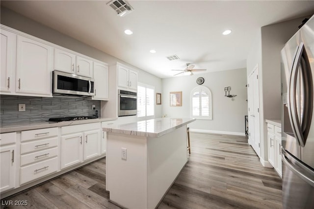 kitchen featuring decorative backsplash, wood finished floors, visible vents, and stainless steel appliances