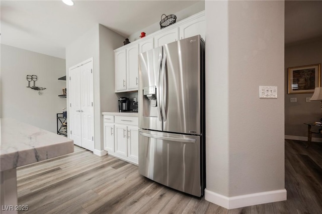 kitchen with white cabinets, baseboards, light wood-style flooring, and stainless steel refrigerator with ice dispenser