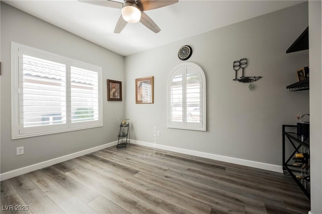 unfurnished room with wood finished floors, a ceiling fan, and baseboards