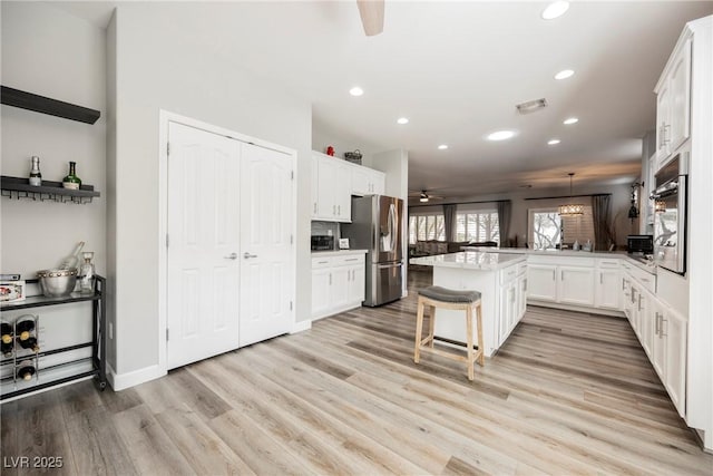 kitchen featuring a ceiling fan, visible vents, a breakfast bar, white cabinets, and appliances with stainless steel finishes