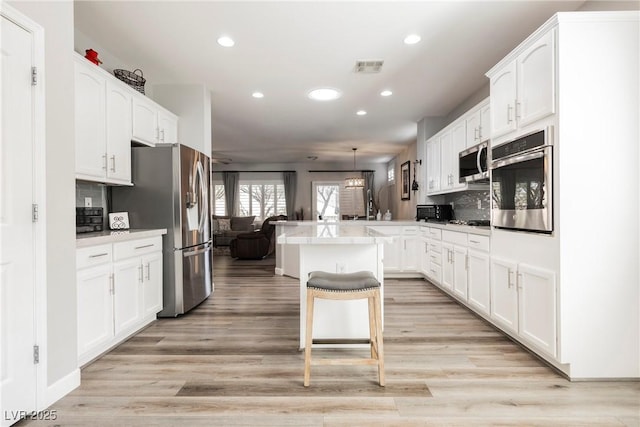 kitchen featuring a peninsula, white cabinets, a breakfast bar area, and stainless steel appliances