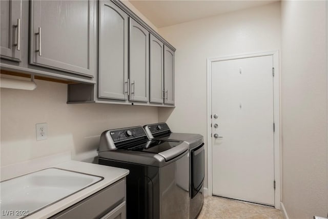 laundry area with light tile patterned floors, baseboards, washing machine and clothes dryer, cabinet space, and a sink