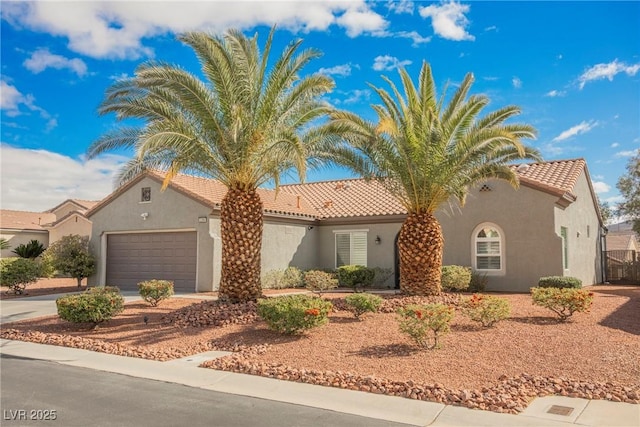 mediterranean / spanish-style home featuring stucco siding, driveway, a tile roof, and a garage