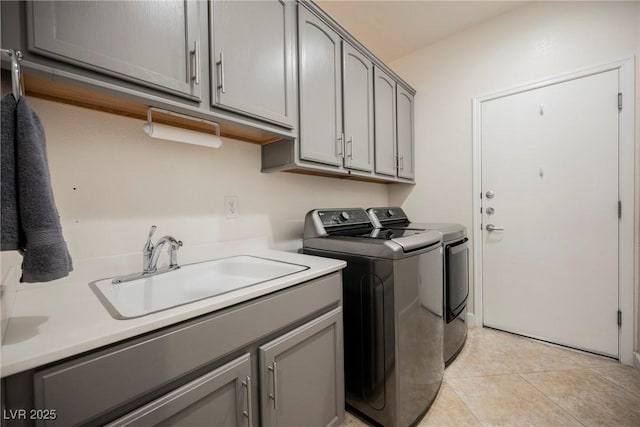 laundry area with washing machine and clothes dryer, cabinet space, light tile patterned flooring, and a sink