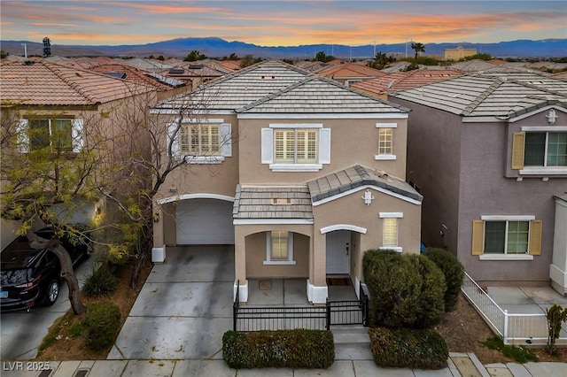 view of front of house with stucco siding, a mountain view, a garage, and driveway