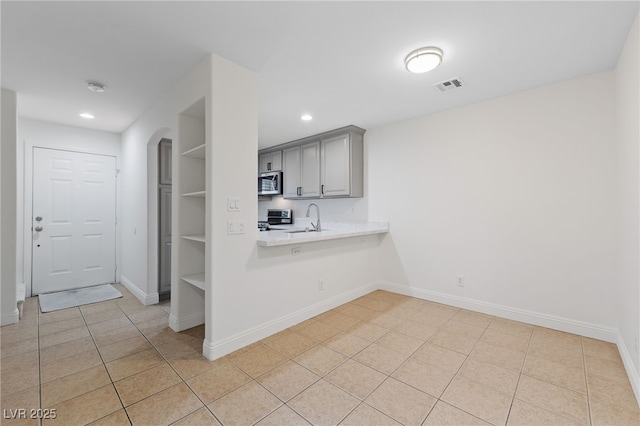 kitchen with visible vents, a sink, stove, light countertops, and stainless steel microwave