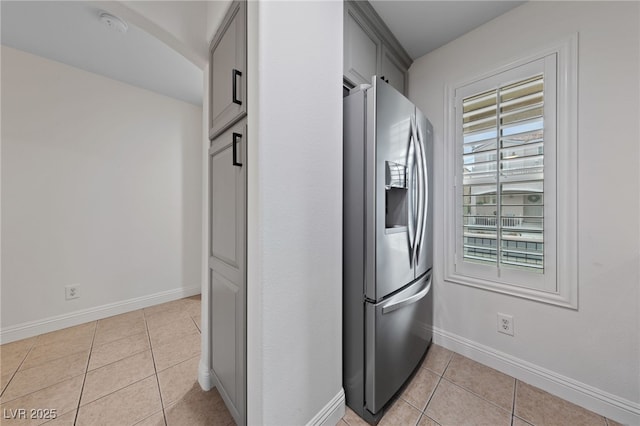 kitchen featuring baseboards, stainless steel fridge, light tile patterned flooring, and gray cabinets