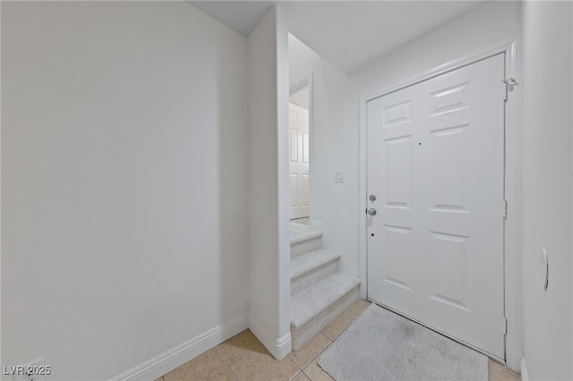 foyer entrance with light tile patterned flooring, stairway, and baseboards