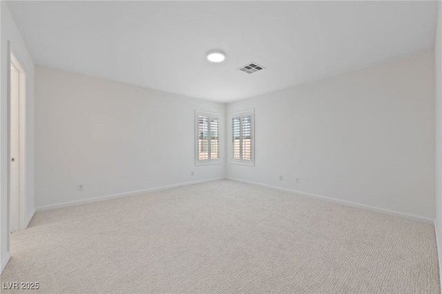 empty room featuring baseboards, visible vents, and light carpet