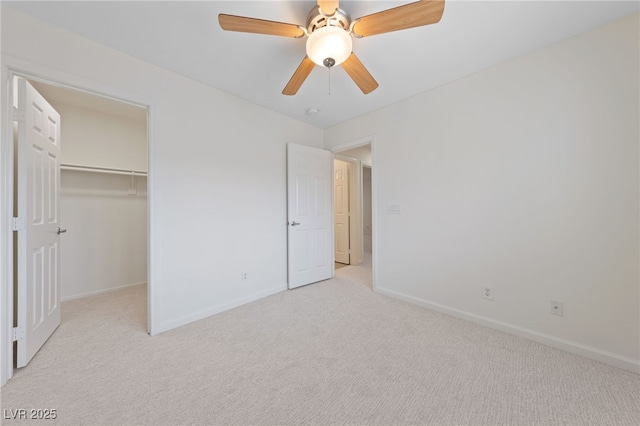 unfurnished bedroom with light carpet, a ceiling fan, a closet, baseboards, and a spacious closet