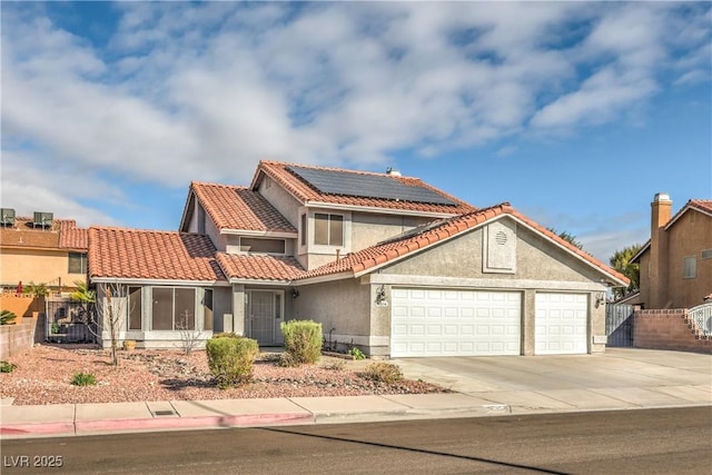 view of front of property featuring fence, stucco siding, concrete driveway, a garage, and roof mounted solar panels