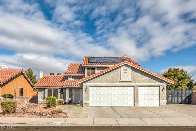 mediterranean / spanish-style home with solar panels, concrete driveway, a tile roof, stucco siding, and a garage