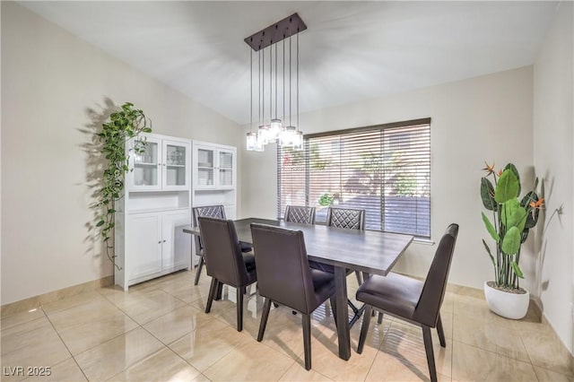 dining room with lofted ceiling, light tile patterned floors, baseboards, and a chandelier