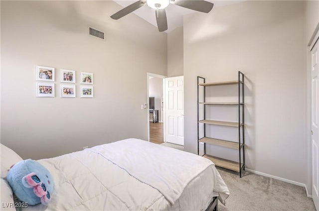 bedroom with baseboards, visible vents, ceiling fan, a towering ceiling, and light carpet