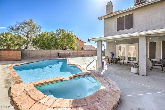 view of swimming pool featuring a pool with connected hot tub, a patio area, and a fenced backyard