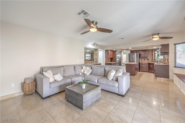 living area with light tile patterned floors, a ceiling fan, and visible vents