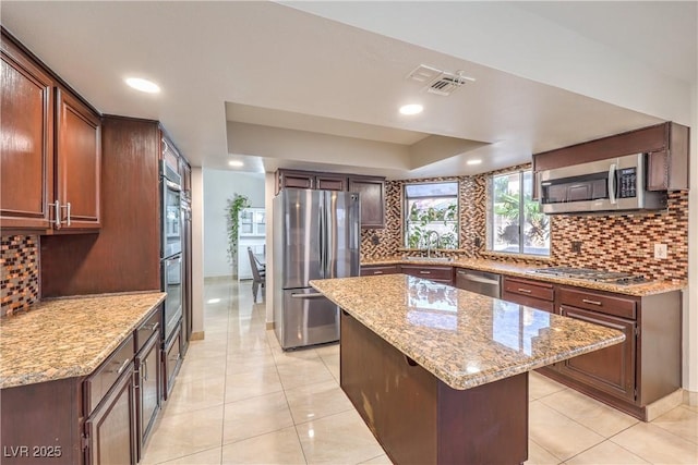 kitchen featuring a sink, backsplash, a center island, appliances with stainless steel finishes, and a raised ceiling