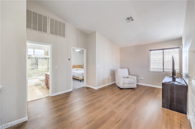 unfurnished room with vaulted ceiling, wood finished floors, and visible vents