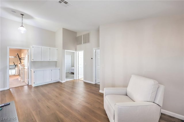 living area featuring visible vents, baseboards, high vaulted ceiling, and wood finished floors