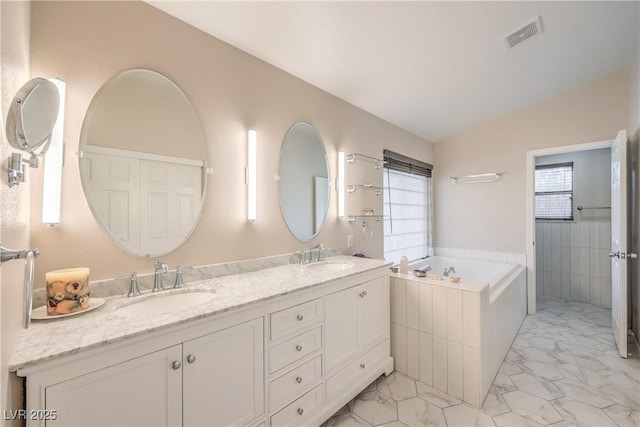 bathroom with a bath, marble finish floor, lofted ceiling, and a sink