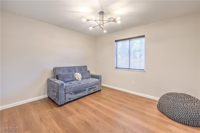 living area featuring a chandelier, baseboards, and light wood-style floors