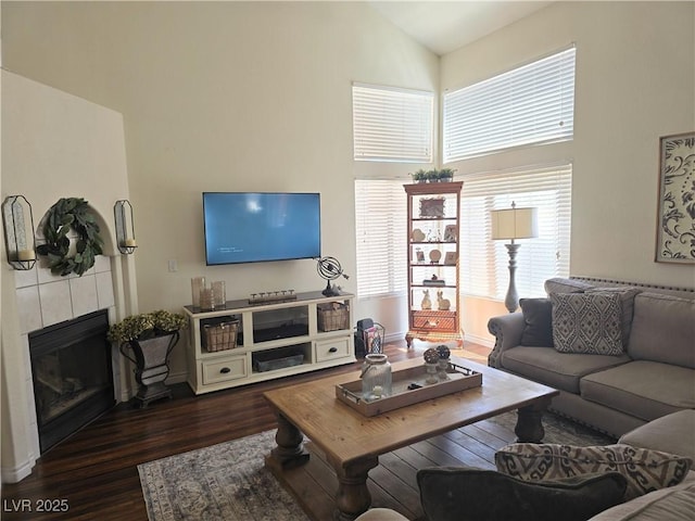 living area with dark wood-type flooring, a fireplace, baseboards, and high vaulted ceiling