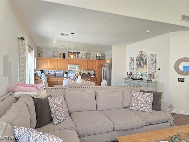 living area with dark wood finished floors, visible vents, and baseboards