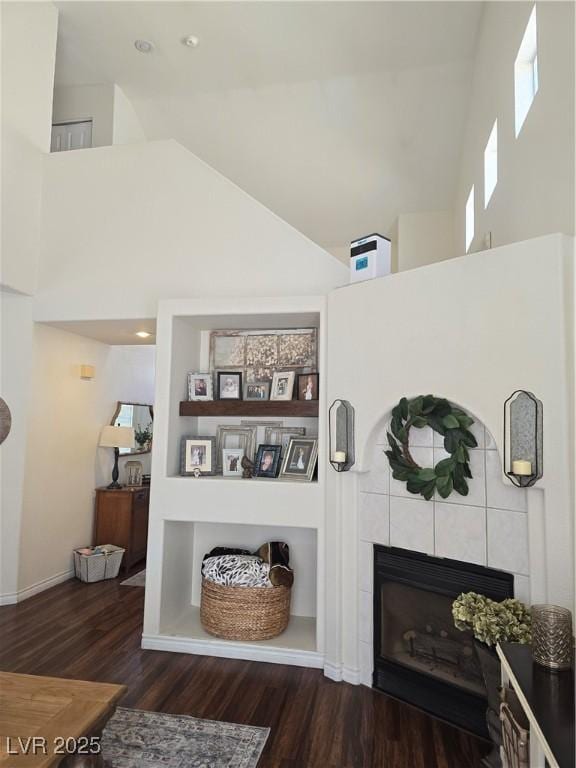 details featuring a tiled fireplace, built in features, and wood finished floors