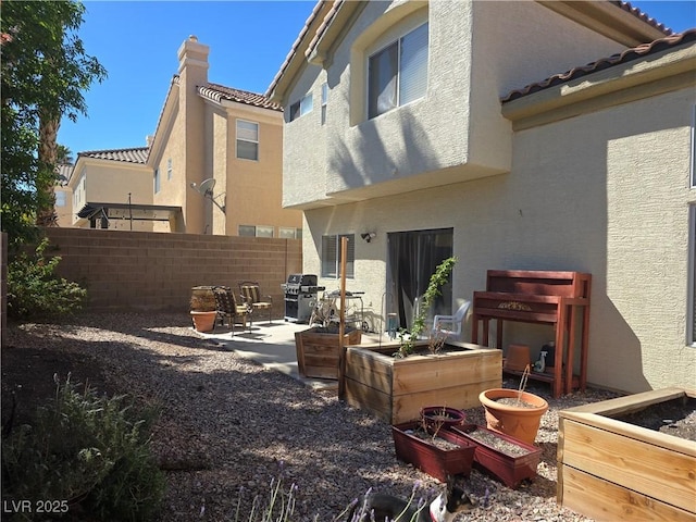 back of house with fence, a garden, stucco siding, a tiled roof, and a patio area