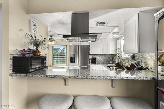 3258 Del Marino St, Las Vegas, NV 89121 - kitchen featuring stainless steel fridge, black microwave, island range hood, a ceiling fan, and a peninsula