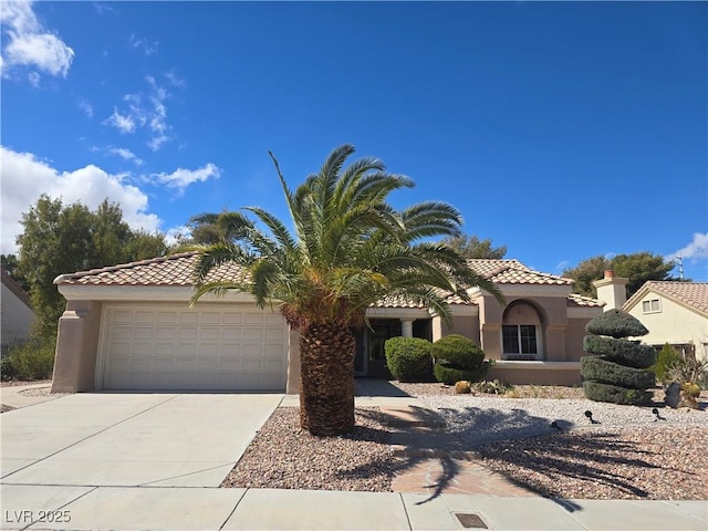 mediterranean / spanish-style house with stucco siding, driveway, an attached garage, and a tiled roof