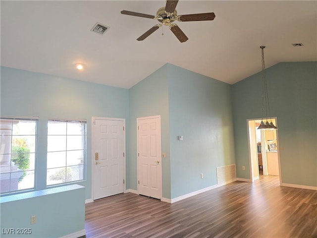 empty room featuring ceiling fan with notable chandelier, lofted ceiling, wood finished floors, and visible vents