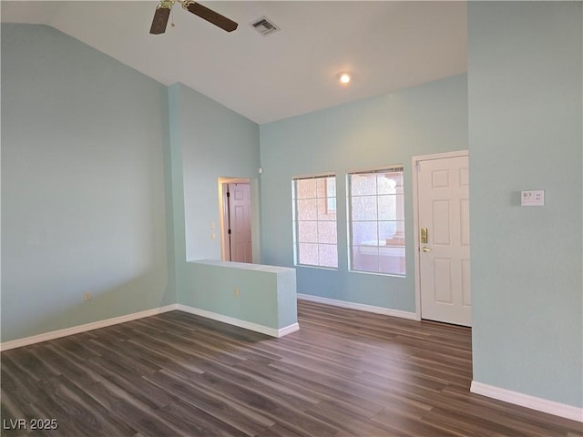 spare room with dark wood-style floors, visible vents, baseboards, ceiling fan, and vaulted ceiling