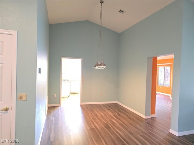 empty room with visible vents, wood finished floors, baseboards, and high vaulted ceiling