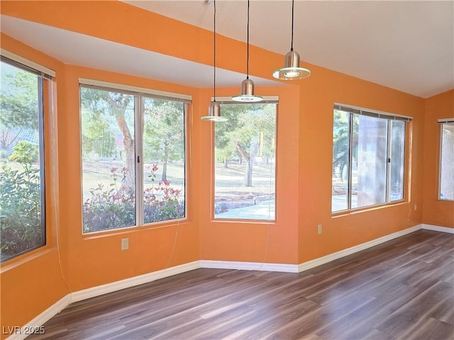 unfurnished dining area with baseboards, lofted ceiling, and dark wood finished floors