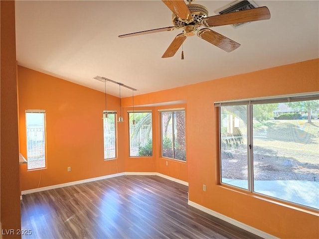 spare room featuring baseboards, lofted ceiling, rail lighting, a ceiling fan, and dark wood-style flooring