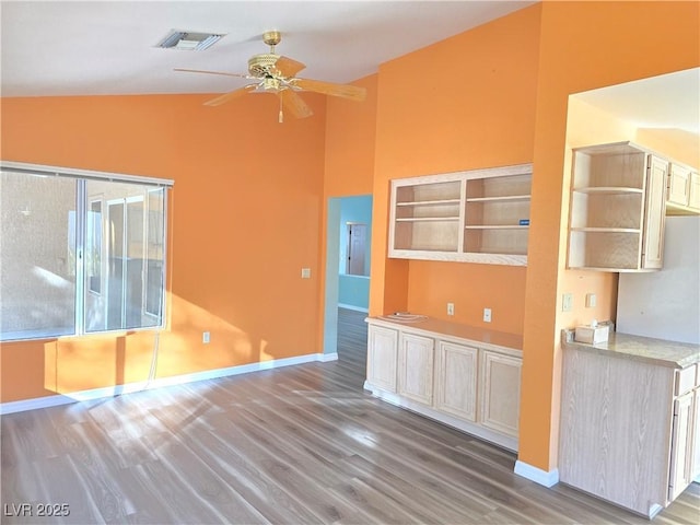 unfurnished room featuring visible vents, wood finished floors, baseboards, ceiling fan, and vaulted ceiling