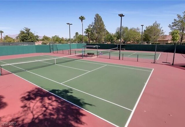 view of tennis court featuring community basketball court and fence