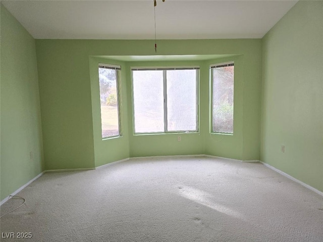 spare room featuring carpet flooring, a healthy amount of sunlight, and baseboards