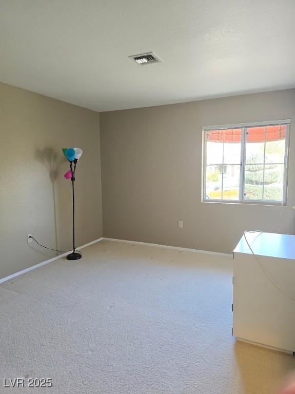 spare room featuring light carpet, visible vents, and baseboards