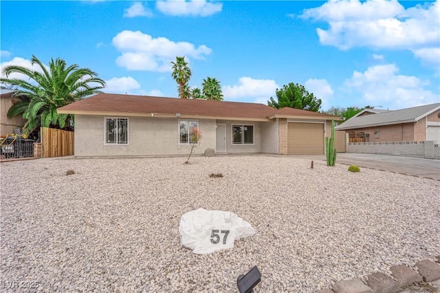 single story home with stucco siding, driveway, an attached garage, and fence