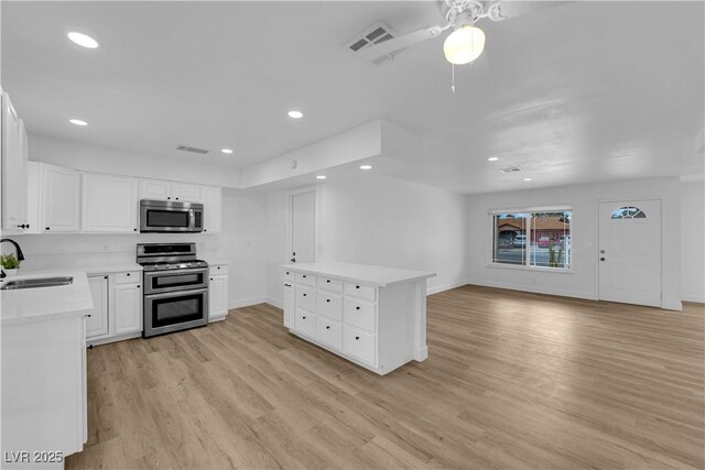 kitchen with light wood-type flooring, a sink, recessed lighting, stainless steel appliances, and light countertops