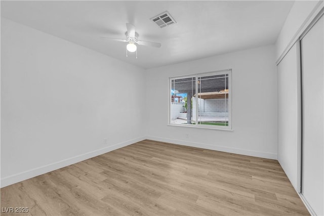 empty room with light wood-type flooring, visible vents, baseboards, and a ceiling fan