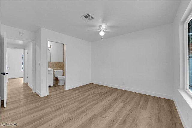 unfurnished bedroom with a ceiling fan, baseboards, visible vents, light wood finished floors, and ensuite bath