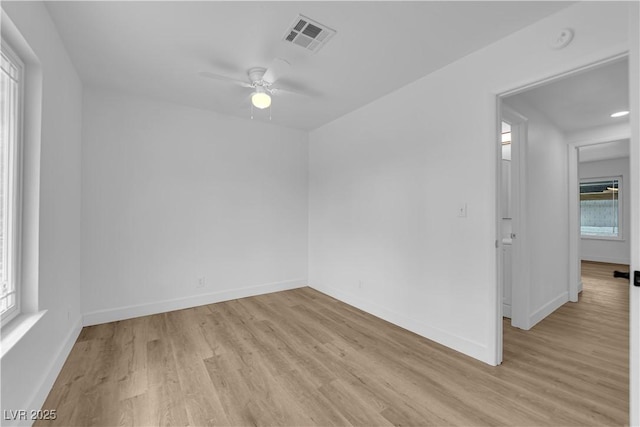 spare room with light wood-style flooring, a ceiling fan, visible vents, and baseboards