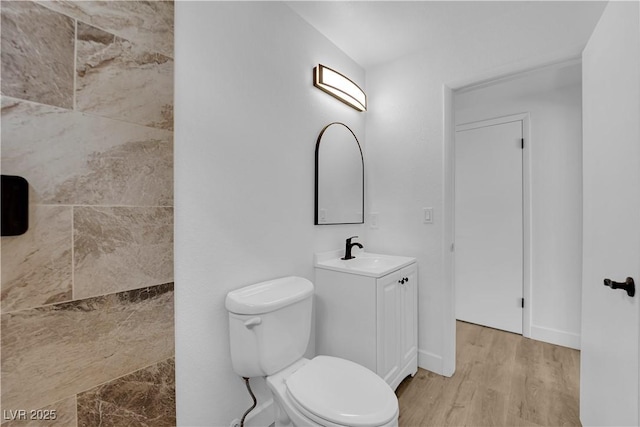 full bath featuring toilet, vanity, baseboards, and wood finished floors