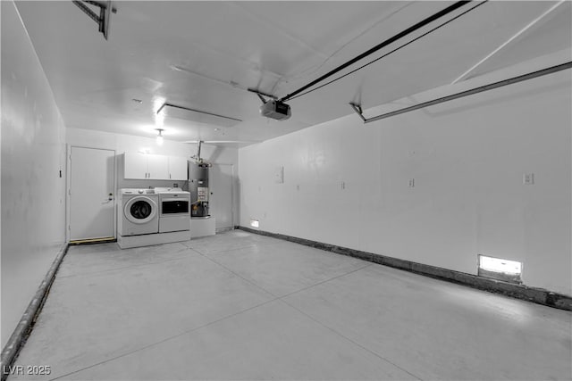 garage featuring baseboards, a garage door opener, water heater, and washing machine and clothes dryer