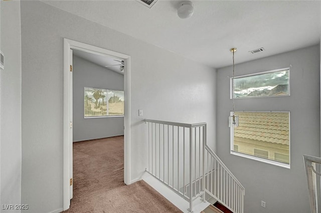 corridor featuring an upstairs landing, visible vents, and carpet