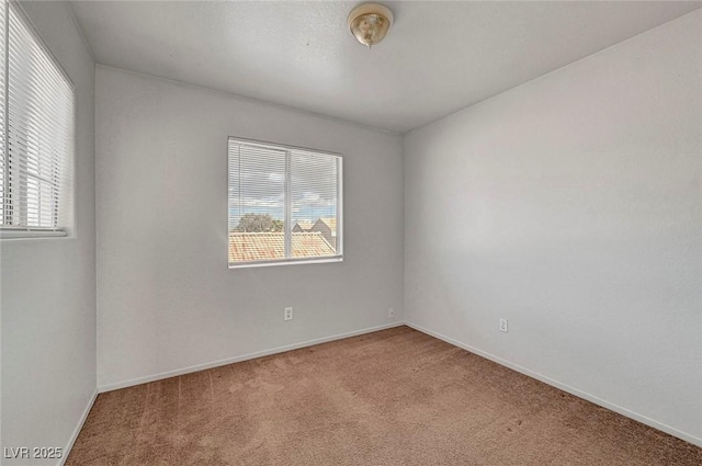 carpeted spare room featuring plenty of natural light and baseboards