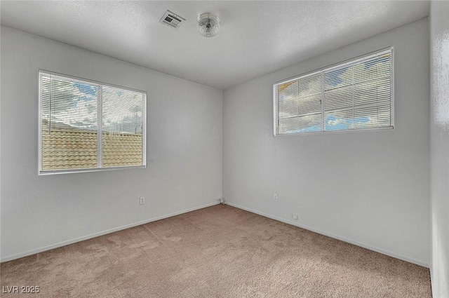 unfurnished room featuring visible vents, carpet flooring, a textured ceiling, and baseboards